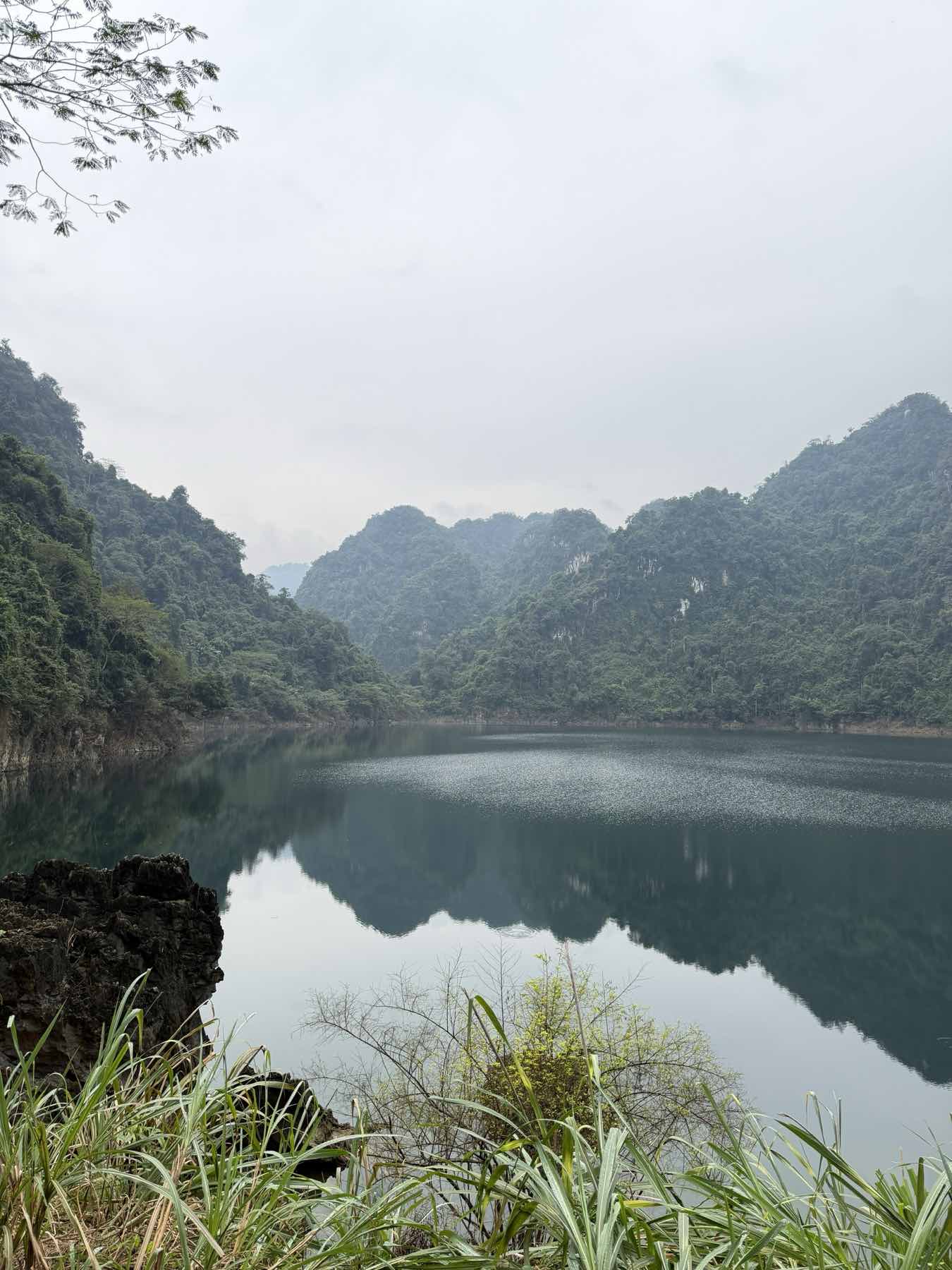 Dawn mist over Hoa Binh lake in northern Vietnam, forested hills closing around still water.